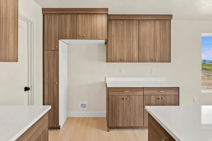 Contemporary kitchen featuring wood-grain cabinetry with gold-tone hardware, white countertops, and light wood-finish flooring