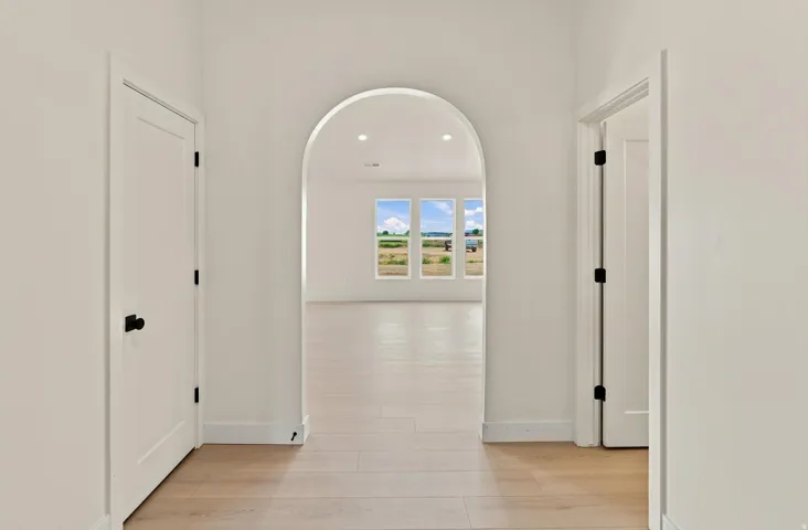 Archway entry to a bright room featuring wood-finish flooring, recessed lighting, and multiple windows