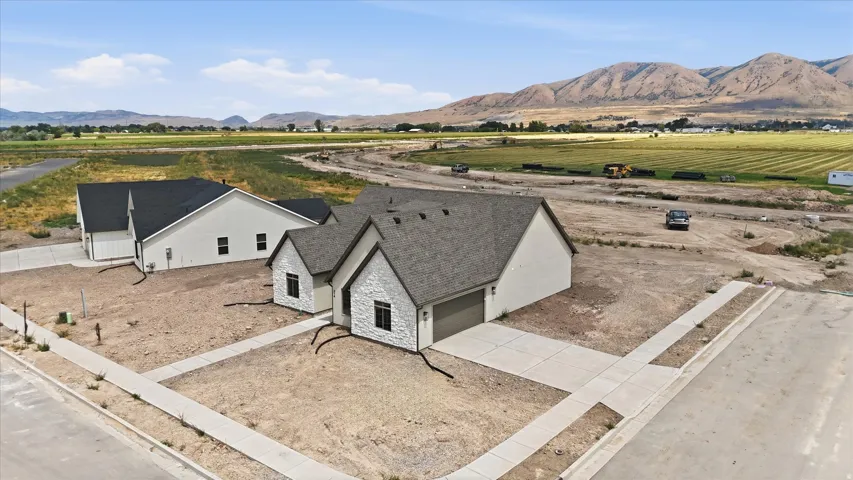 Newly constructed residence featuring a light-toned exterior with stone accents, dark-framed windows, and a dark shingled roof