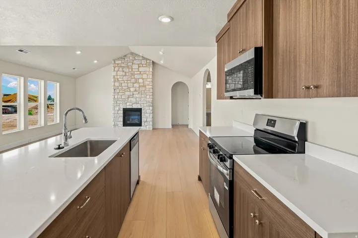 Kitchen featuring a large island with an undermount sink, light wood-finish cabinetry, stainless steel appliances, and white countertops