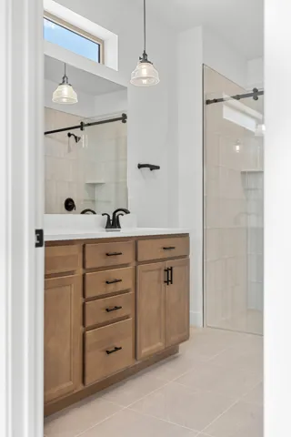 Bathroom vanity featuring light wood cabinetry with dark hardware, a white countertop, and a built-in sink with a dark faucet