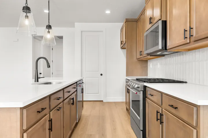 Modern kitchen featuring light wood-finish cabinetry with black hardware, white countertops, and a white subway tile backsplash