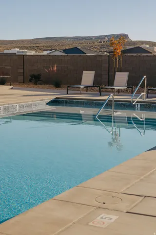 Outdoor swimming pool with concrete decking, surrounding desert landscaping, and a privacy wall
