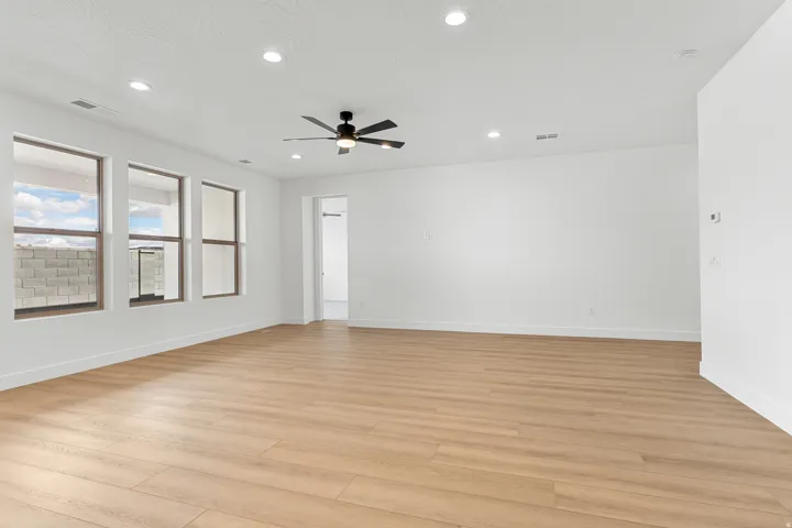 Spacious room featuring wood-finish flooring, recessed lighting, and a contemporary ceiling fan