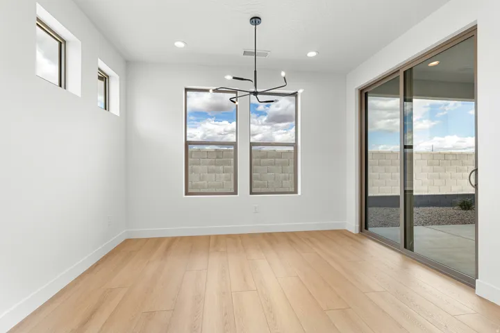 Bright interior space featuring light wood-finish flooring, a modern linear chandelier, and recessed lighting