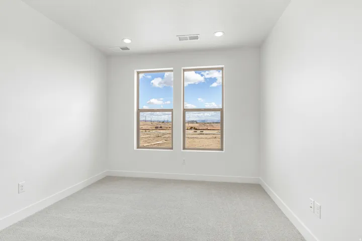 Bright interior space featuring two large windows, recessed ceiling lighting, textured ceiling, light-toned carpet, and clean white baseboards