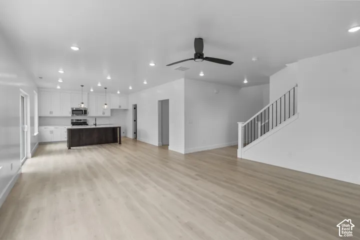 Open-concept living space featuring wood-finish flooring, recessed lighting, and a modern ceiling fan