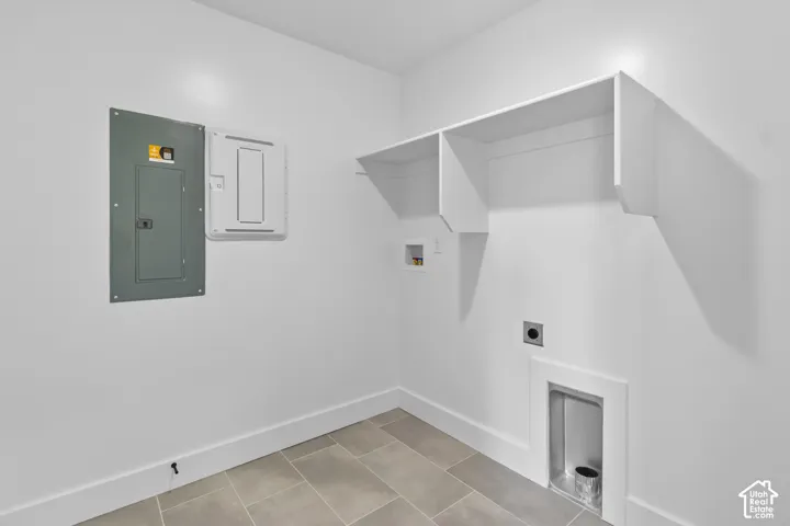 Utility room featuring neutral-toned tile flooring, white baseboards, and built-in white shelving