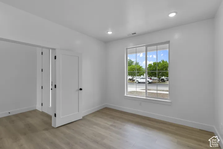 Bright room featuring wood-finish flooring, recessed lighting, and a large multi-pane window