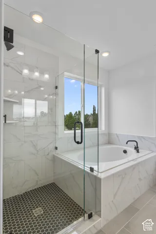 Walk-in shower with black hexagonal tile flooring and clear glass enclosure