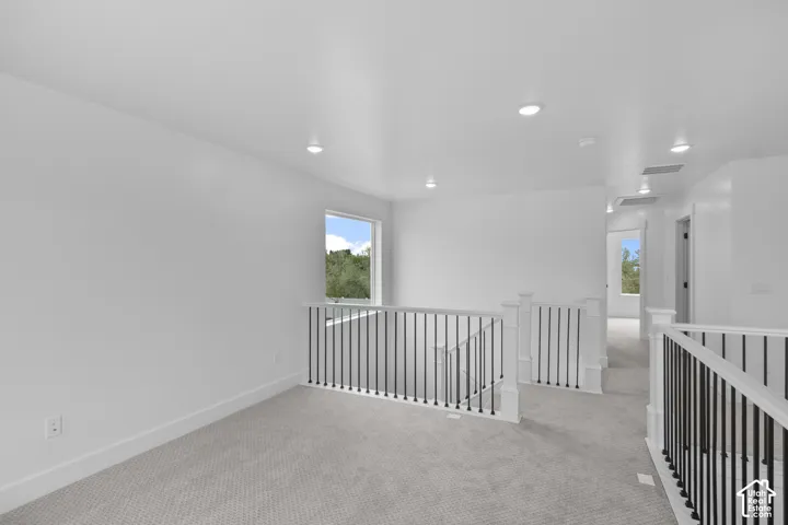 Open loft area featuring recessed lighting, a window with outdoor scenery, and carpet flooring