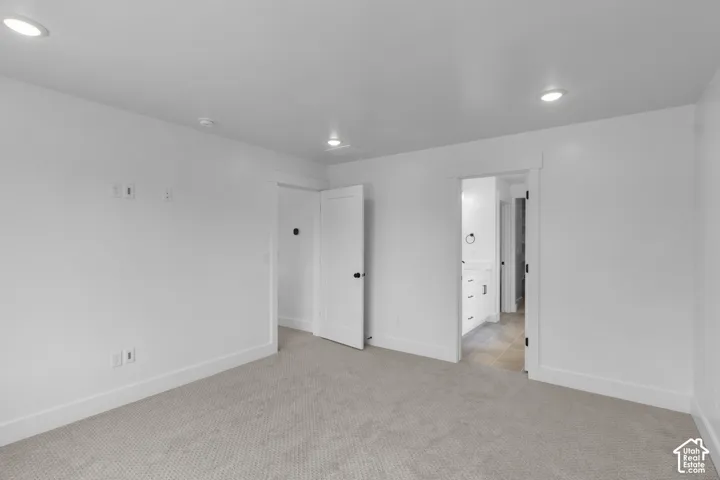 Neutral tone carpet flooring with white baseboards, white walls, and recessed lighting