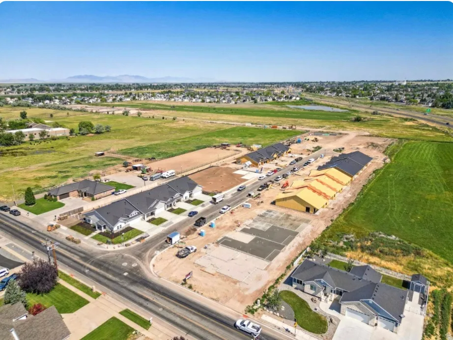 Development site featuring new construction homes with dark shingle roofs, light-colored exteriors, and landscaped front yards