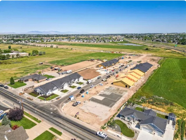 Development site featuring new construction homes with dark shingle roofs, light-colored exteriors, and landscaped front yards