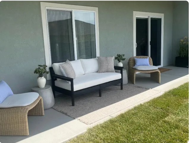 Concrete patio with stucco exterior, featuring two sliding glass doors and a manicured lawn