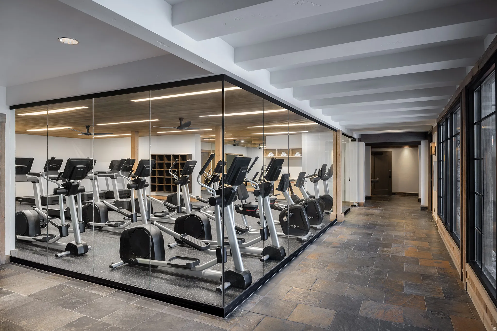 Dedicated fitness center featuring glass partitions and a rubber mat flooring