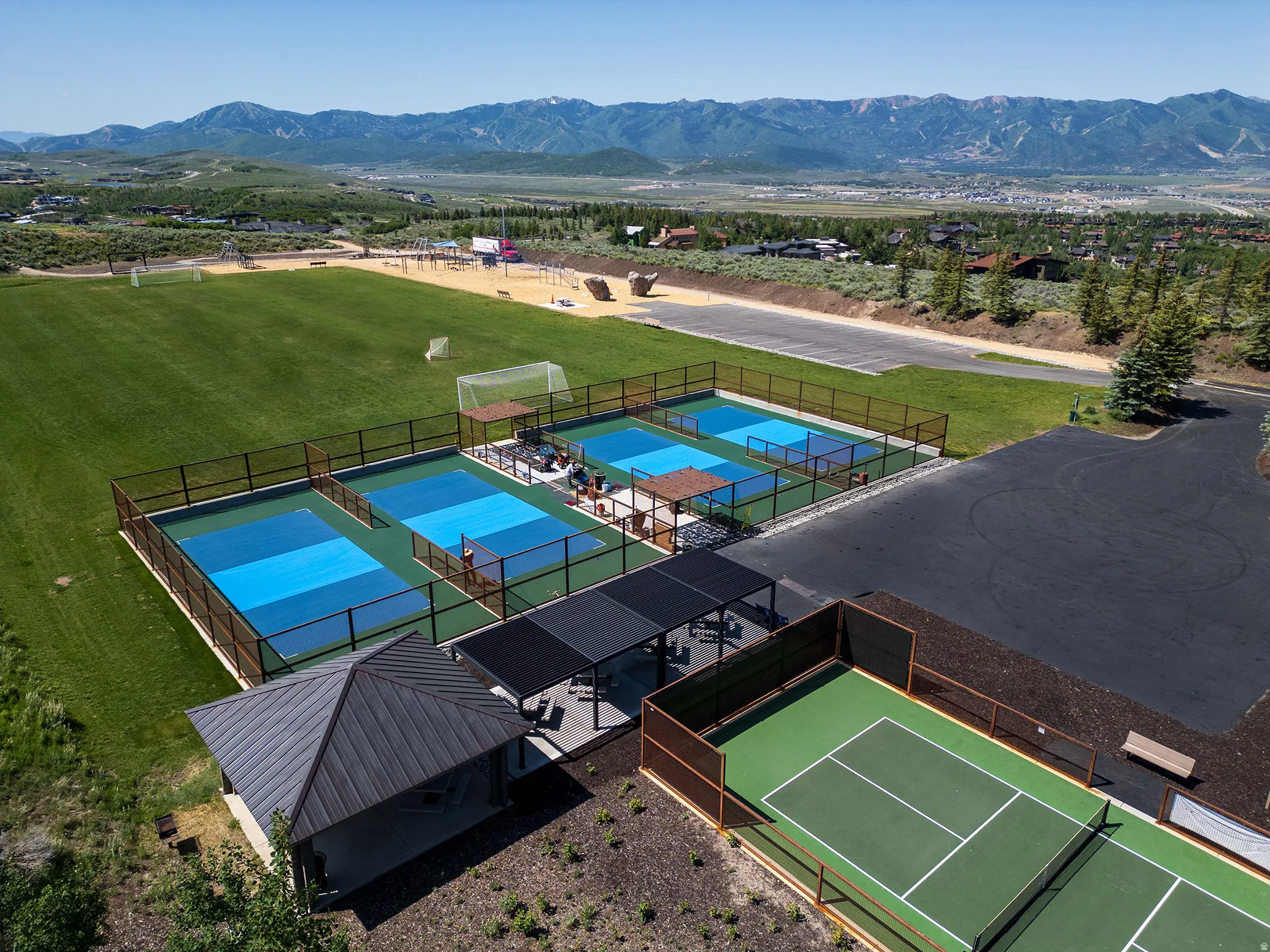 Expansive recreational grounds featuring multiple pickleball courts, a tennis court, and a large grass field