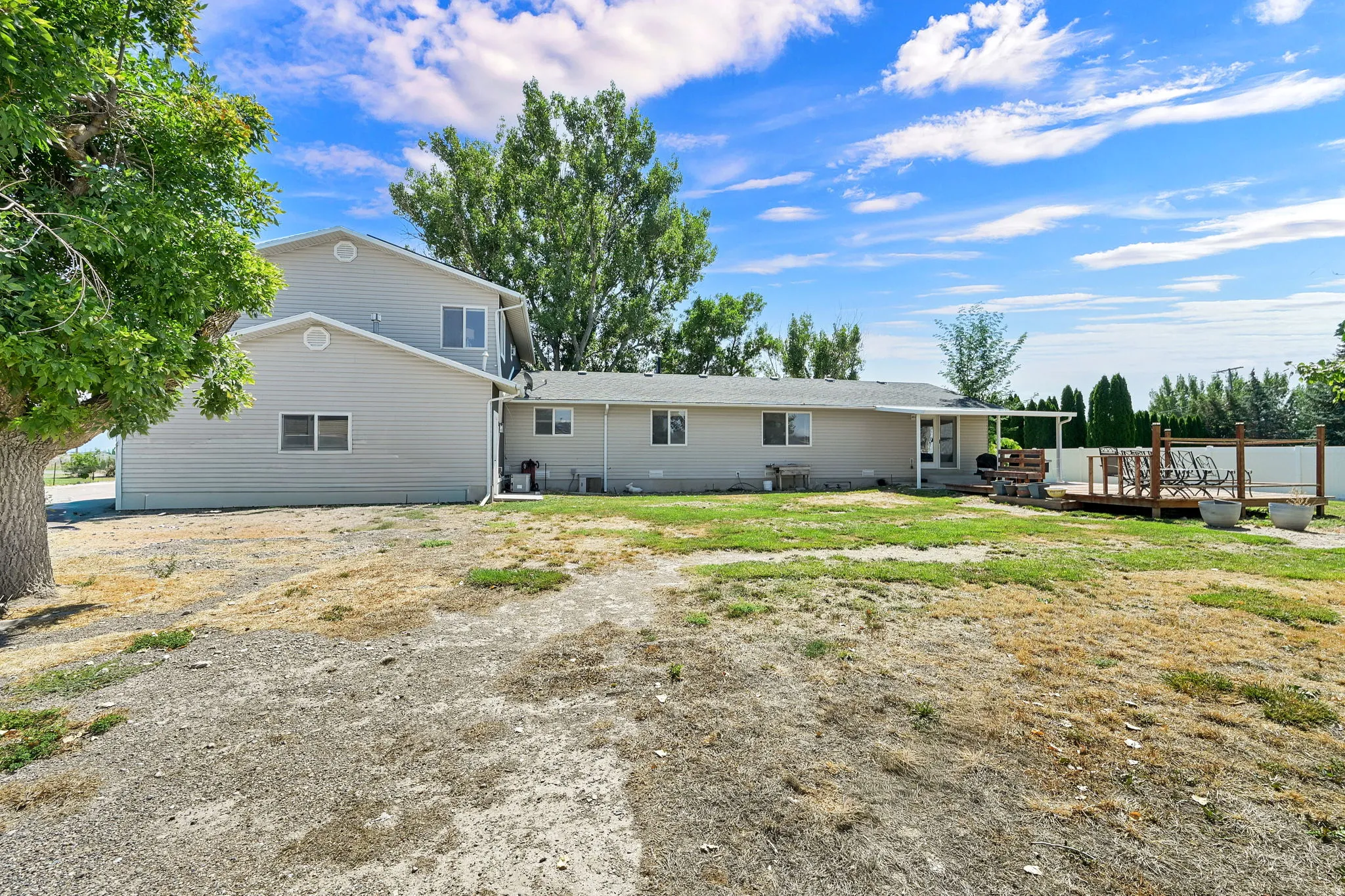 Expansive backyard featuring a multi-level composite deck, covered patio, and mature trees