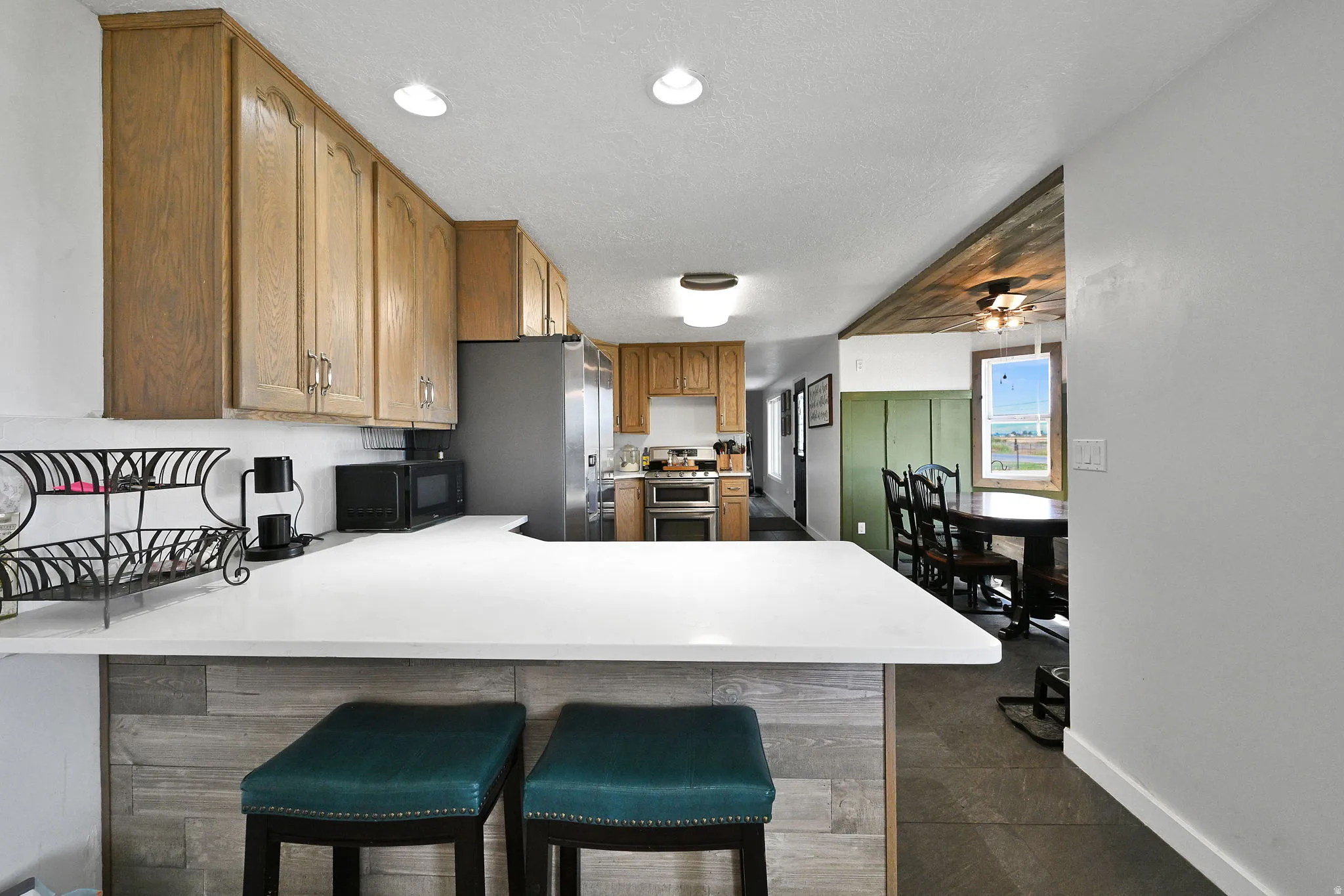 Kitchen featuring light wood cabinetry, a white countertop peninsula, stainless steel appliances, and wood-finish flooring