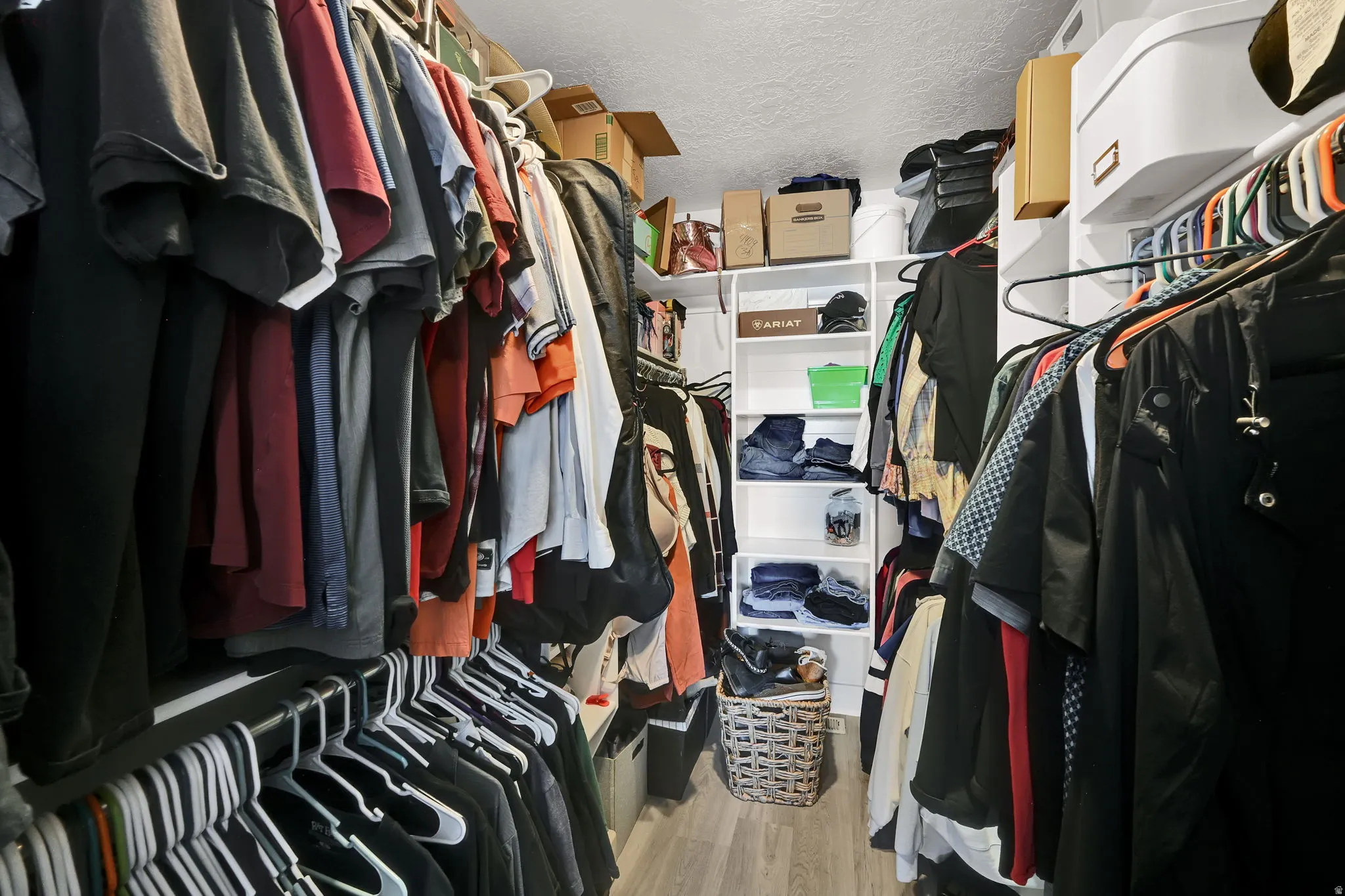 Walk-in closet featuring wood-finish flooring, built-in shelving, and multiple hanging rods for organization