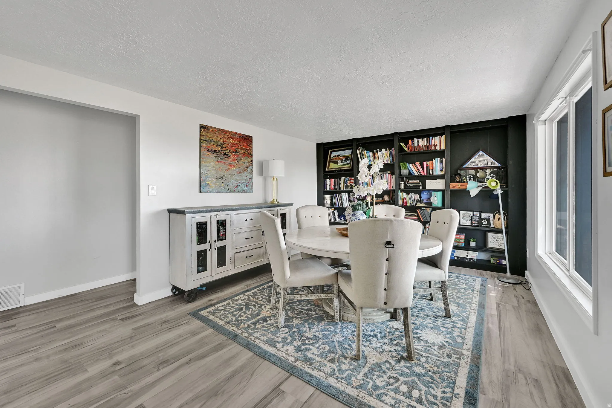 Spacious room featuring wood-finish flooring, a built-in shelving unit, and multiple windows