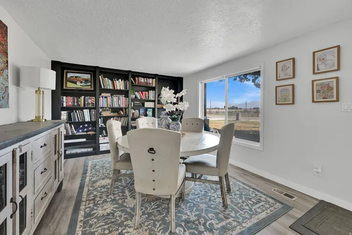 Spacious dining area featuring a wide window, built-in shelving, light wood-finish flooring, and light gray walls