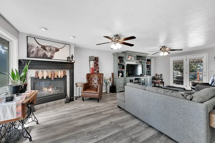 Living area featuring wood-finish flooring, a fireplace with a black mantel, recessed lighting, and two ceiling fans
