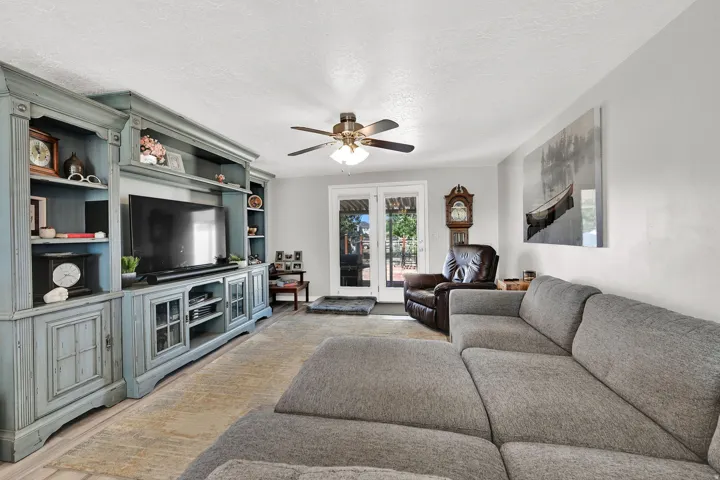 Spacious living area featuring a custom built-in entertainment center, ceiling fan, and French doors providing outdoor access