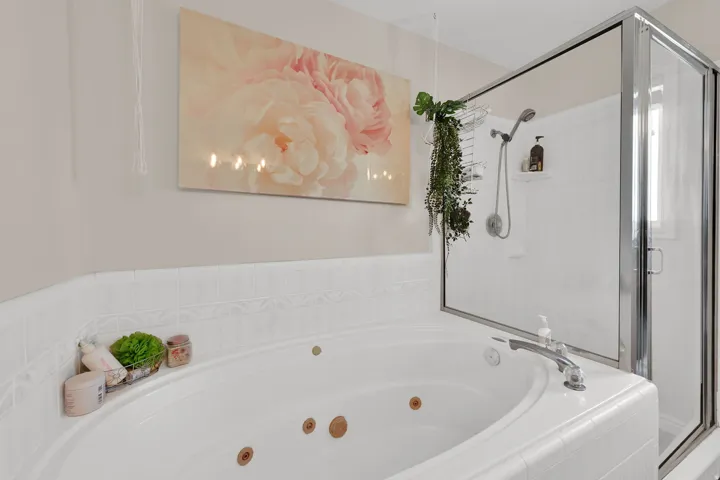 White jetted tub with chrome fixtures, surrounded by white tiled walls