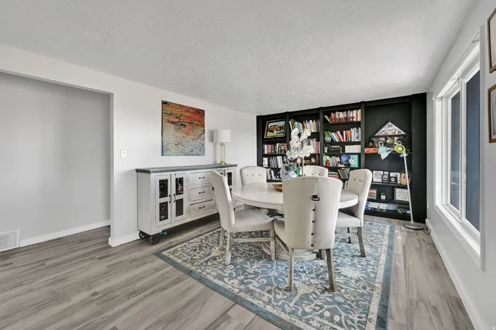Spacious room featuring wood-finish flooring, a built-in shelving unit, and multiple windows