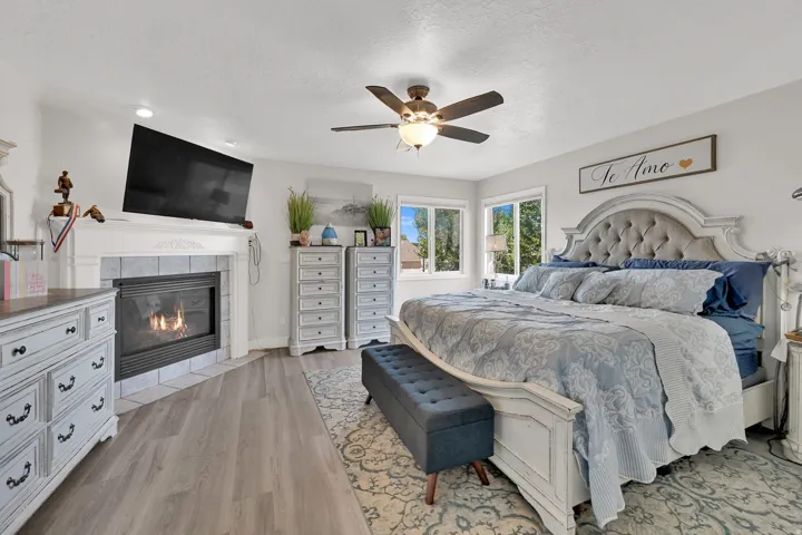 Spacious bedroom featuring wood-finish flooring, a ceiling fan, and multiple windows