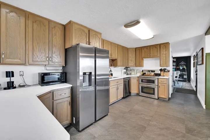 Expansive kitchen featuring wood-finish cabinetry, white countertops, and stainless-steel appliances
