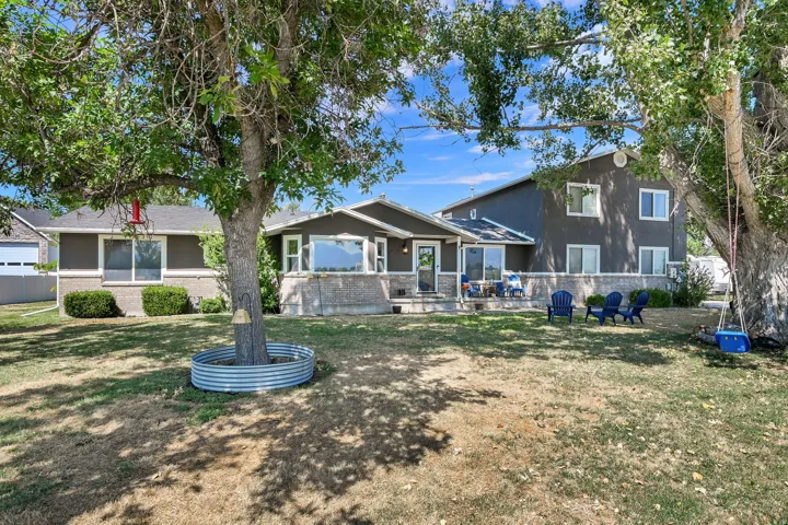 Expansive backyard featuring mature trees, a patio area, and a multi-level exterior facade with stone accents