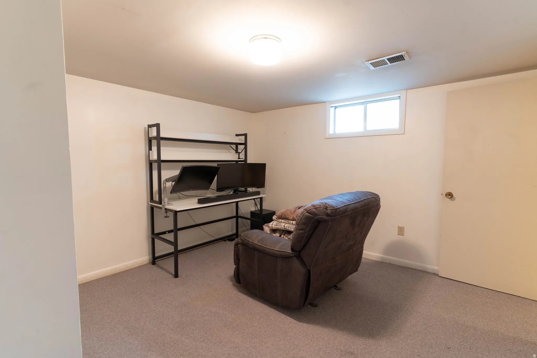 Carpeted room featuring a single window, white walls, and a white ceiling with a flush-mount light fixture