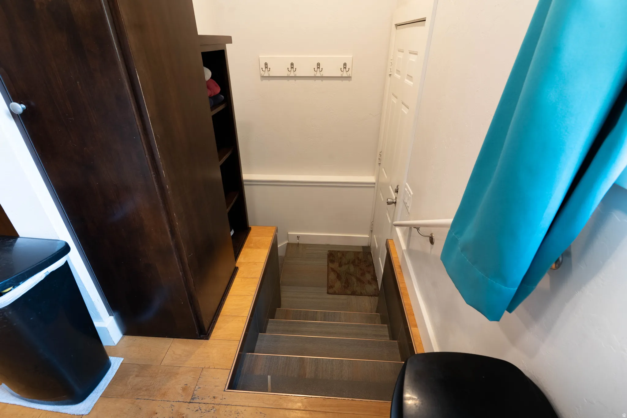 Wood-finish flooring at the landing leading to a staircase with laminate finished stairs.