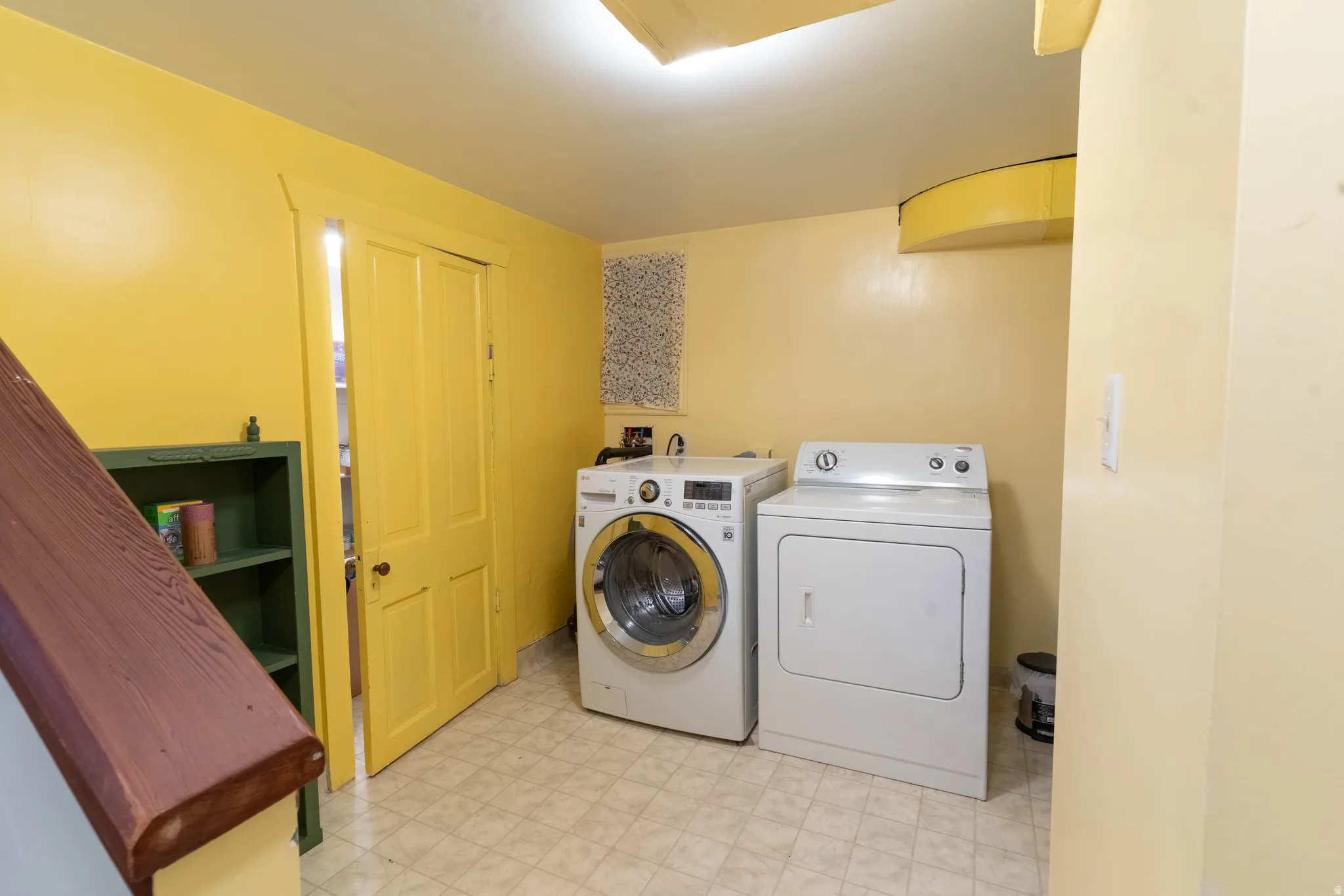 Laundry area featuring a front-loading washing machine, a top-loading dryer, and durable vinyl flooring