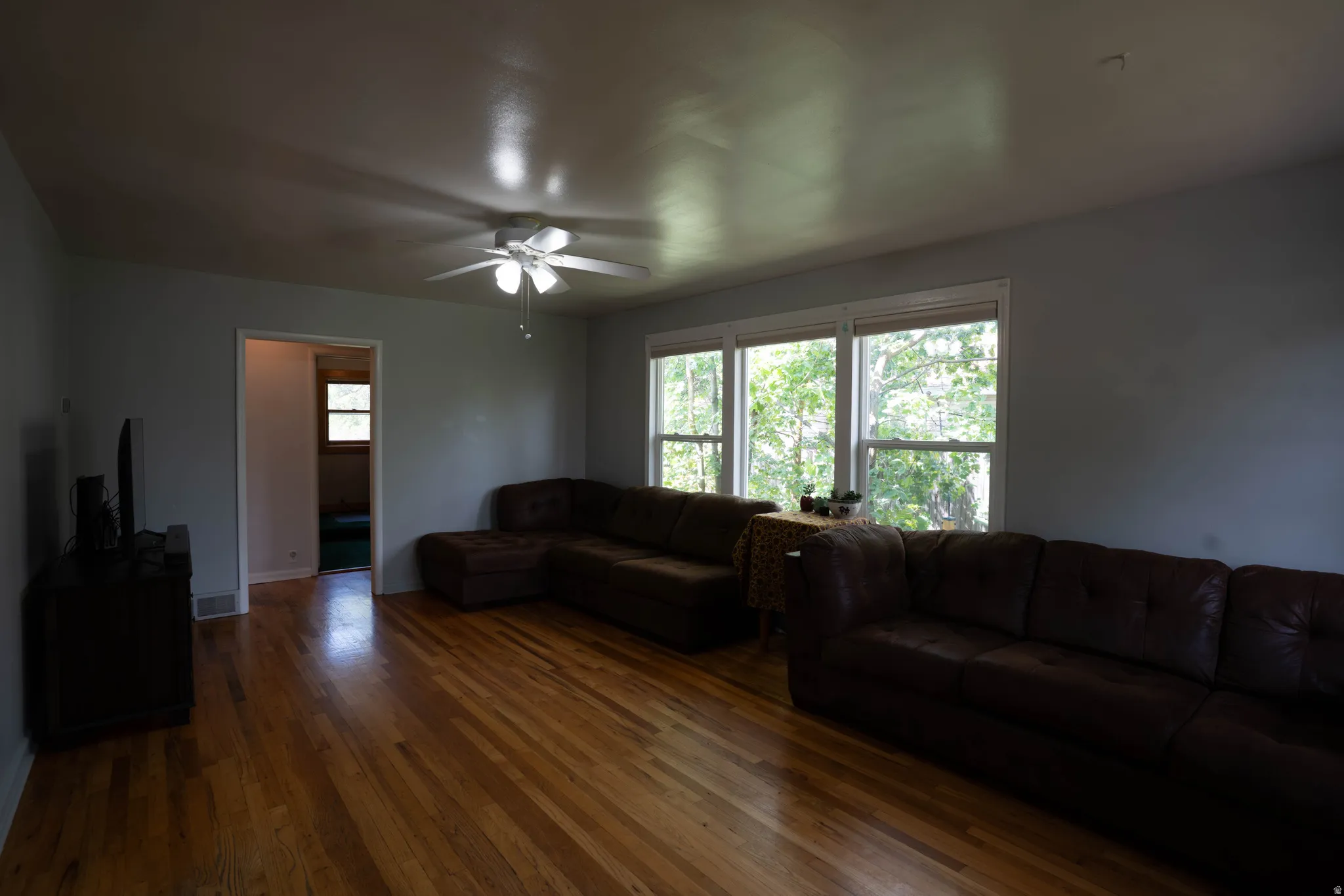 Hardwood-finish flooring extending throughout the room, complemented by a ceiling fan with integrated lighting