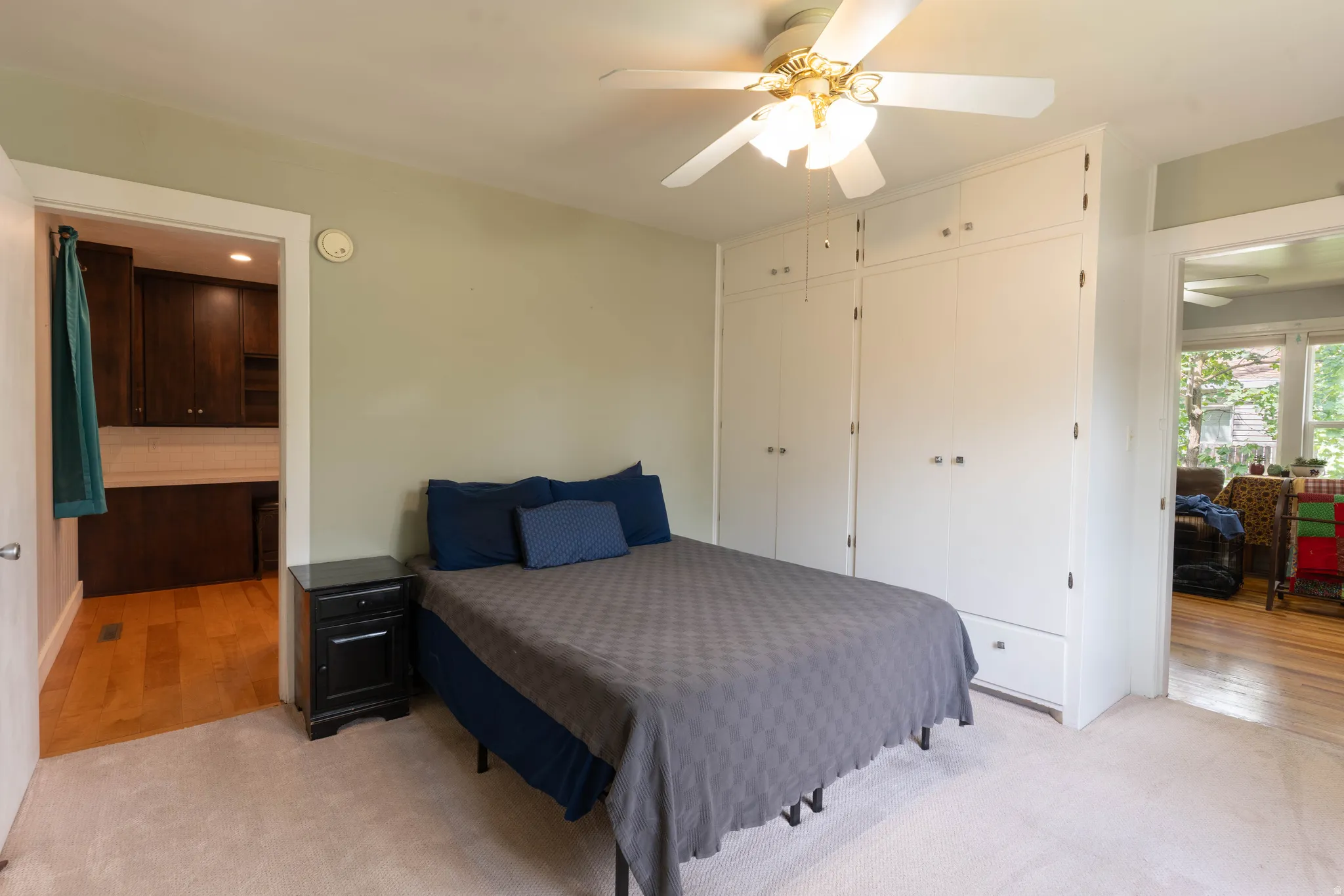 Bedroom featuring light-colored carpeting, a ceiling fan with integrated lighting, and built-in closets with drawers.