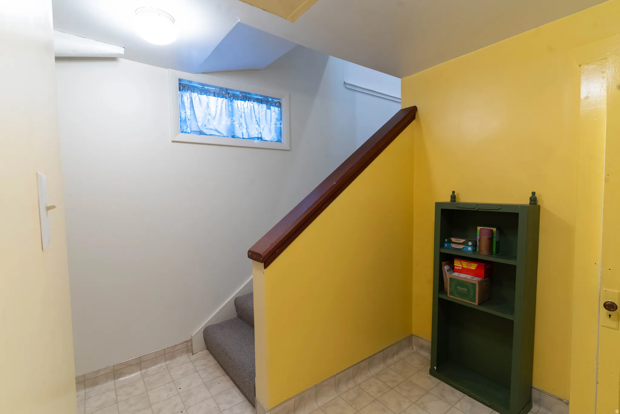 Carpeted staircase featuring a wood handrail and small storage area under the steps.