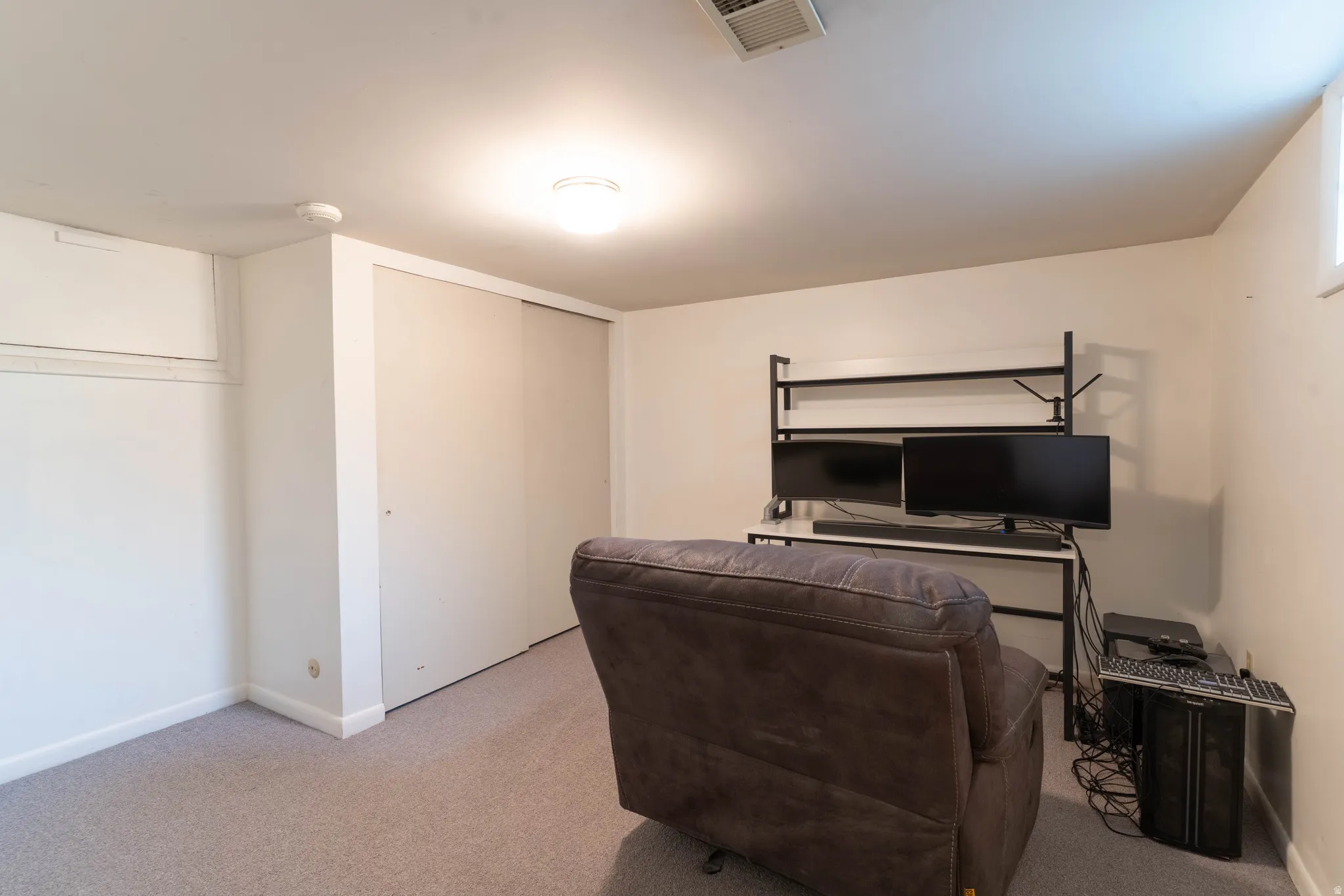 Carpeted room with a flush-mount ceiling light fixture, white walls, and white baseboards