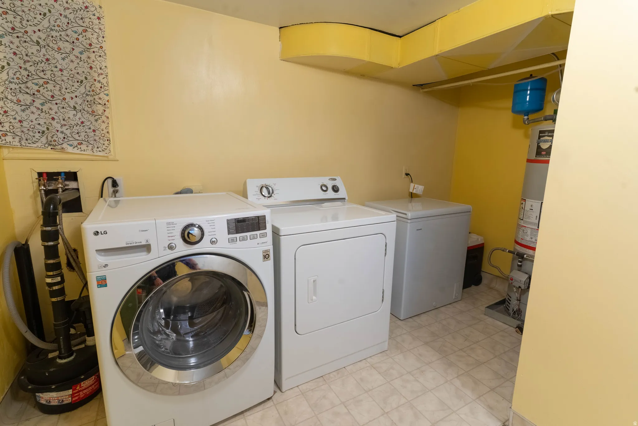 Dedicated laundry space featuring a front-loading washing machine, clothes dryer, and tiled flooring