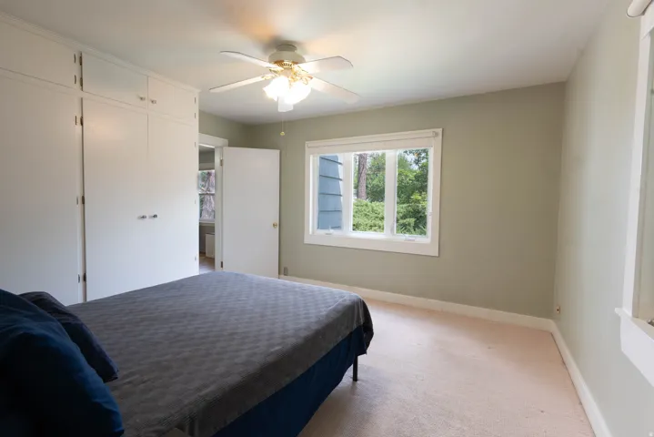 Bedroom featuring built-in closet, neutral wall color, and a ceiling fan and light. More gerat windows