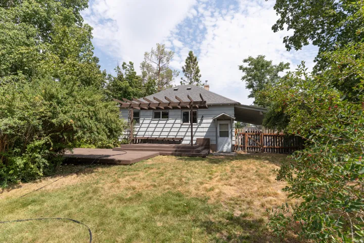 Rear exterior featuring a multi-level deck with a pergola, horizontal siding, and a covered side entrance to carport .