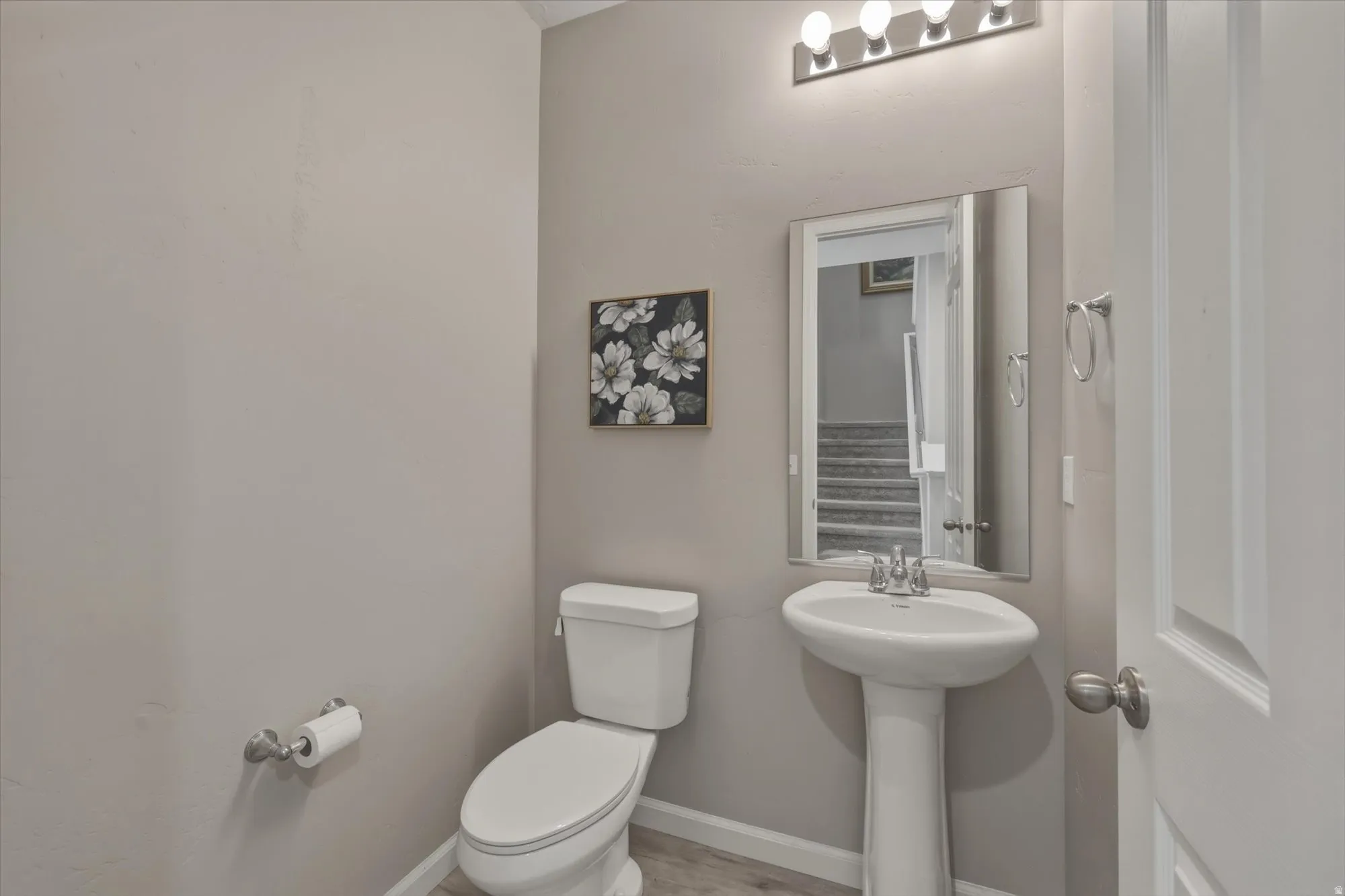 Pedestal sink with chrome faucet, square mirror, and a contemporary four-bulb vanity light fixture
