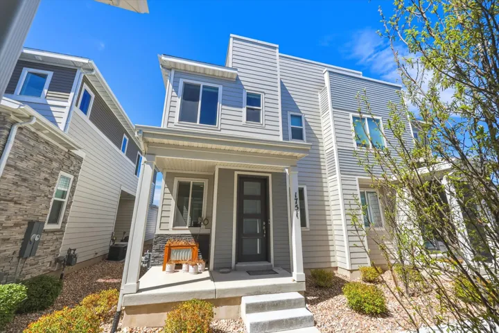 Contemporary townhouse exterior featuring a covered front porch, multi-pane windows, and a combination of horizontal siding and stone veneer accents