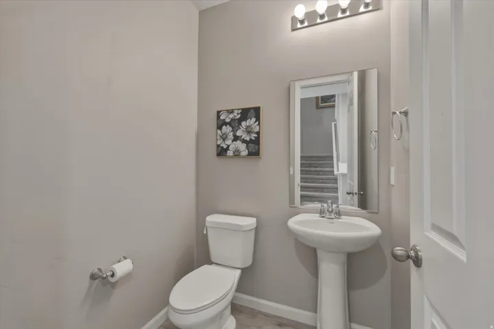 Pedestal sink with chrome faucet, square mirror, and a contemporary four-bulb vanity light fixture