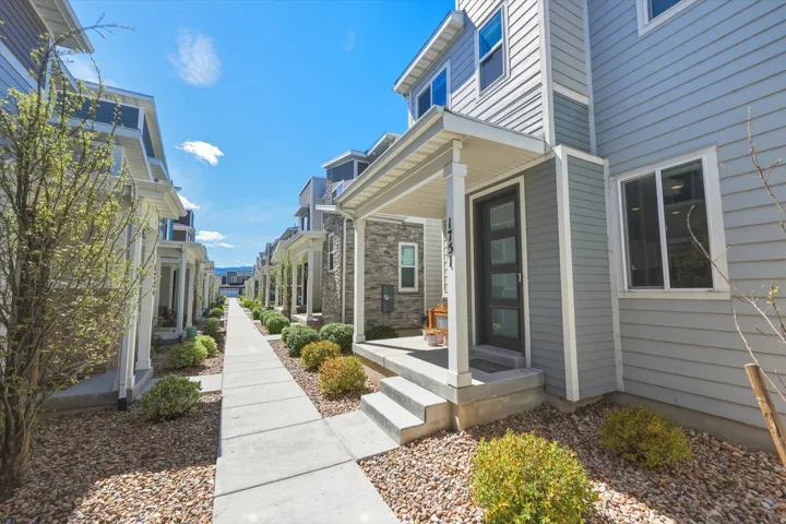 Modern townhome exterior featuring light gray horizontal siding and stone veneer accents