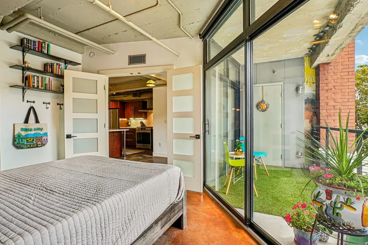 Floor-to-ceiling sliding glass doors open to a private balcony featuring artificial turf