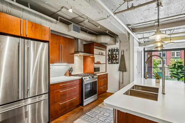 Modern kitchen featuring stainless steel appliances, wood-finish cabinetry, and white countertops