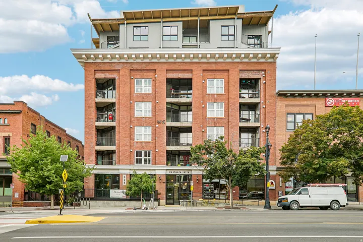 Brick facade apartment building with multiple balconies and ground-level retail spaces